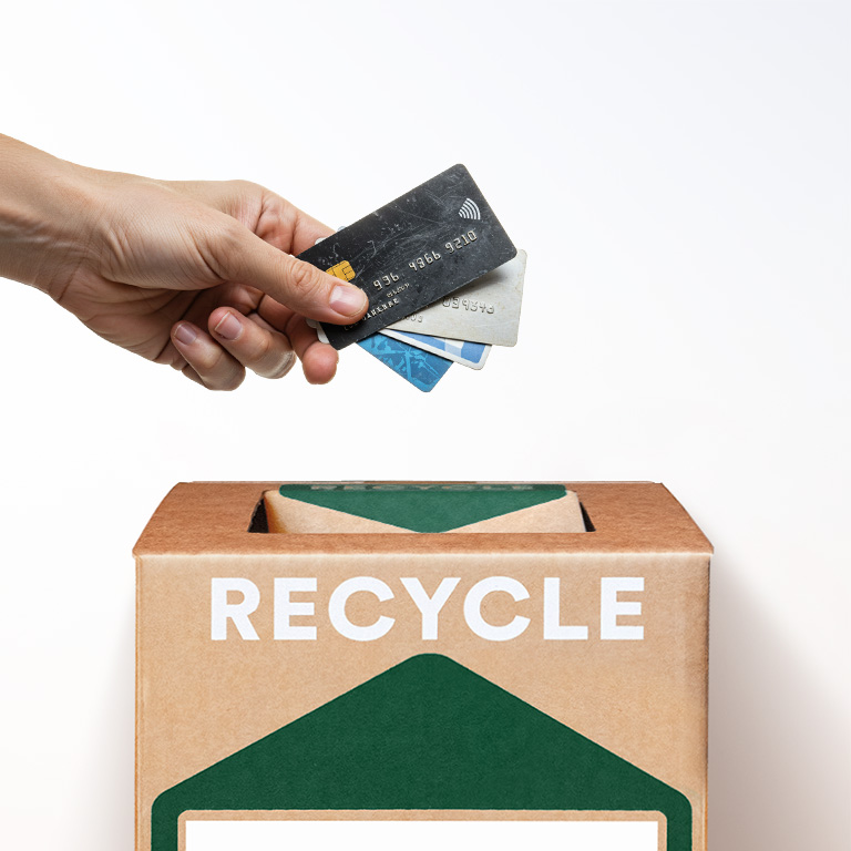 A hand placing several payment cards into a Zero Waste Box