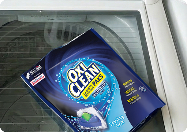 Empty OxiClean laundry pod pouch placed on top of a washing machine.